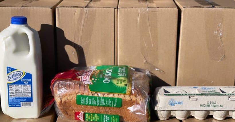 A carton of milk, a loaf of bread and a carton of eggs set on top of packed boxes