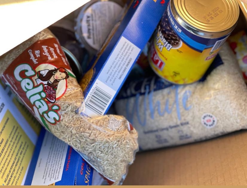 A box packed with rice, pasta, and tinned beans and corn