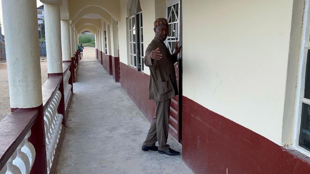 A man standing in a finished clinic corridor, walls painted red and white