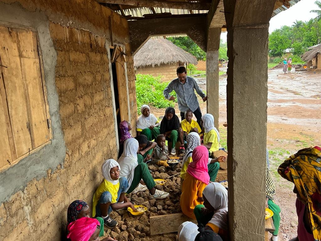 Women breaking stone by hand under a shelter, producing the aggregate used in the building work