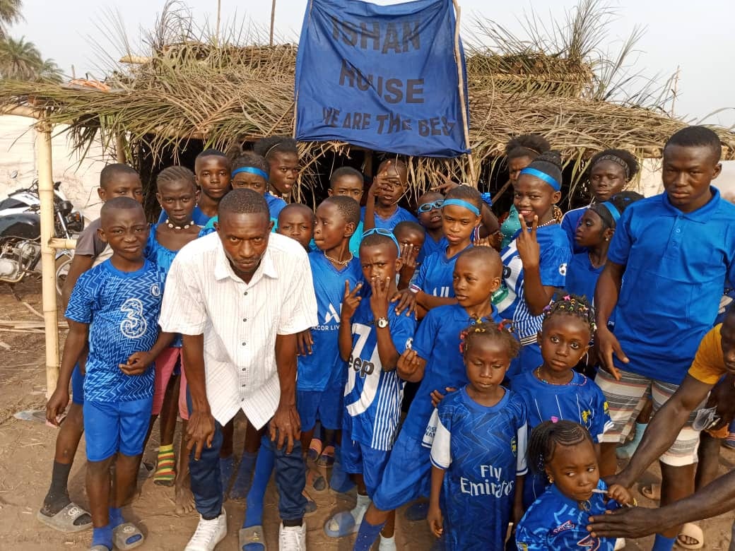 School children in blue uniforms standing with their teacher outside a classroom