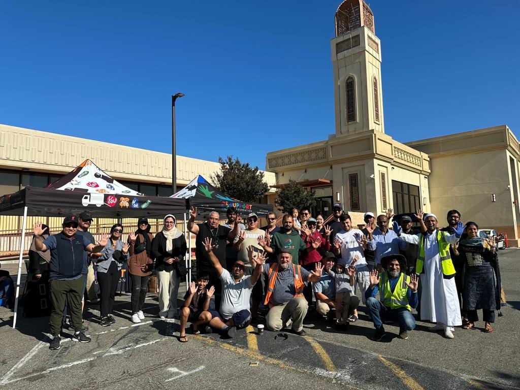 Around sixty YANA volunteers posed together outside a mosque under a clear blue sky, before a delivery morning